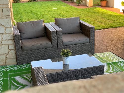 two wicker chairs and a table on a patio at Relaxing Getaway Beachfront Access Multi Family Pets Mandurah in Mandurah