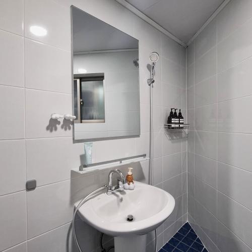 a white bathroom with a sink and a mirror at Dear Home in Daegu