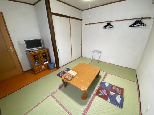 a living room with a wooden table and a tv at Zao Base スキー場から徒歩1分 in Yamagata
