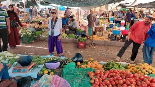 a woman standing in a market with fruits and vegetables at Dar Amadine in Imlil