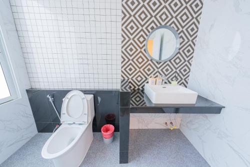a bathroom with a toilet and a sink and a mirror at Homey House Na Jomtien in Na Jomtien