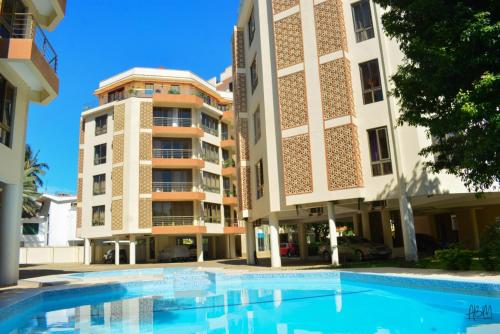 a swimming pool in front of a building at MichMal Homes in Mombasa