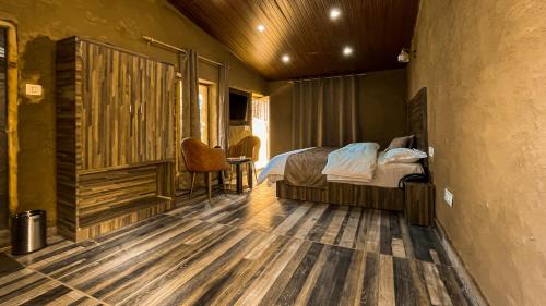 a bedroom with a bed and a wooden floor at Basho Mud Huts in Vashisht