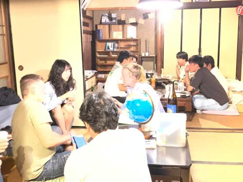 a group of people sitting around a table in a room at Guesthouse SETOUCHI LIFE in Kure