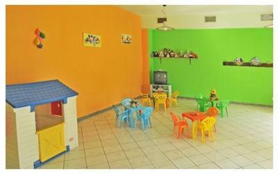 una sala de juguetes con mesas y sillas y una pared verde en Hotel Stella Bianca, en Scarmagno