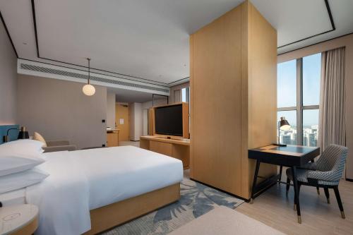 a hotel room with a bed and a desk and a television at Hilton Garden Inn Danzhou Yangpu in Danzhou
