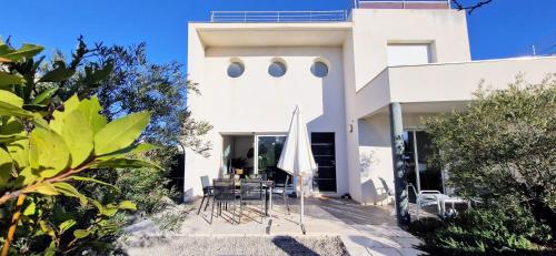 une maison blanche avec une table et un parasol blanc dans l'établissement LA CATALANE, Villa Contemporaine en Bord de Mer et Climatisée, à Sète