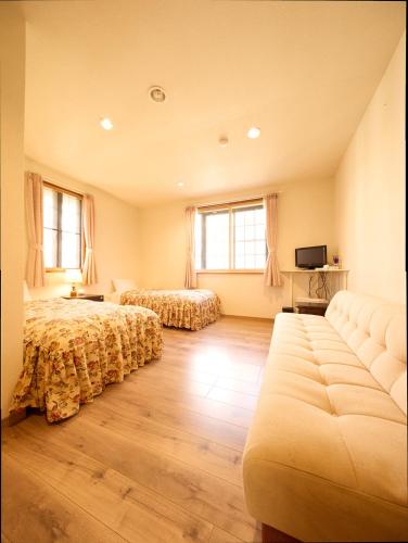 a bedroom with two beds and a couch at カナリアンホテル in Tateshina