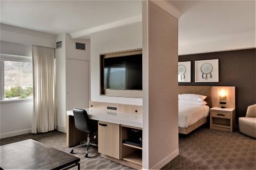 a hotel room with a bed and a desk with a television at Delta Hotels by Marriott Kamloops in Kamloops