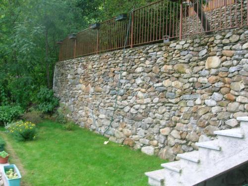 a stone retaining wall with stairs and a fence at B&B Al Carotin in Mantello