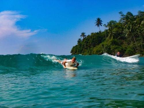 a man riding a wave on a surfboard in the ocean at Clear Point Studio in Dickwella