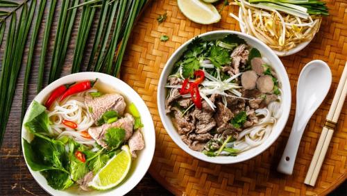 a table with two bowls of noodles and meat and vegetables at Khách sạn Tây Bắc Tam Đảo in Tam Ðảo