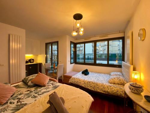une chambre avec deux lits, une table et des fenêtres dans l'établissement Appartement Passy PARIS, à Paris