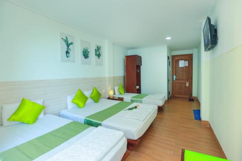 a room with two beds with green and white pillows at My Hotel Quy Nhơn in Quy Nhon