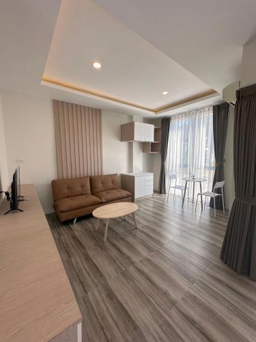 a living room with a brown couch and a table at Sleep At Airport in Nai Yang Beach