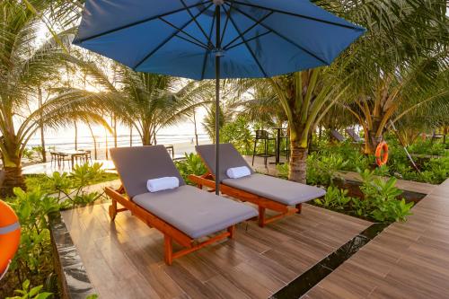 two chairs and an umbrella on a deck with palm trees at Langco Bay Retreat in Lang Co