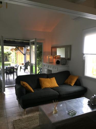a living room with a black couch and a table at Villa Mäenma in Le Teich