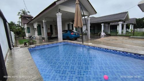 a blue swimming pool in front of a house at Tiffana Homestay in Kampong Ayer Terjun