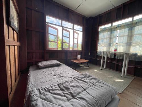 a bedroom with a bed in a room with windows at Stay with sumo homestay in Chiang Mai