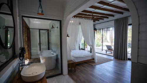 a bathroom with a bedroom with a tub and a sink at Lov Faralya Adults Only in Faralya
