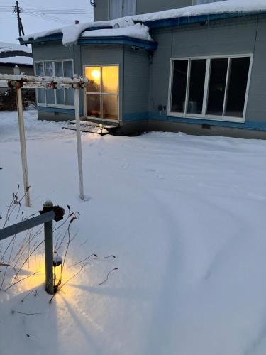 a house with a snow covered yard in front of it at Private Lodging KASE 五所川原 in Goshogawara