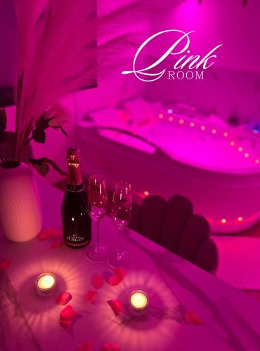 Cette chambre rose comprend des verres à vin et une baignoire. dans l'établissement Pink Room by Loveroomeo, à Pontarlier