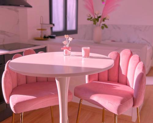 une table rose avec des chaises roses et une table blanche dans l'établissement Pink Room by Loveroomeo, à Pontarlier
