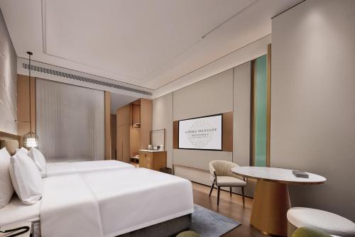 a bedroom with a large white bed and a table at Grand Mercure Chengdu East in Chengdu
