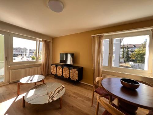a living room with a table and two windows at UP&GREAT Apartments - Stylish City Living in Zürich