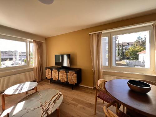 a living room with a table and two windows at UP&GREAT Apartments - Stylish City Living in Zürich