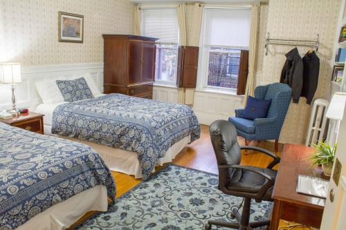 a hotel room with two beds and a chair at Beacon Inn 1750 in Brookline