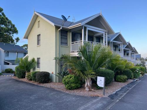 a house with palm trees in front of it at Raffertys Resort Lakeside Terrace Plus 4 Star in Cams Wharf