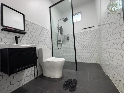 a bathroom with a shower and a toilet and a sink at The Gelam House in Kampong Telaga Papan