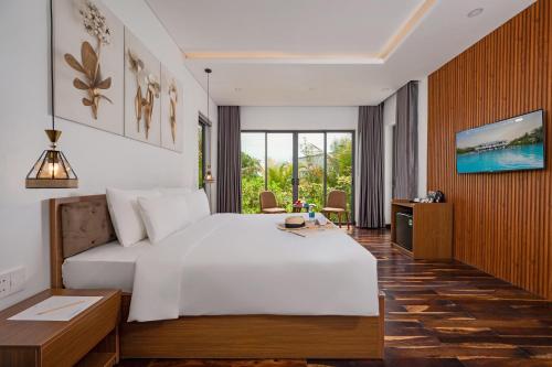 a bedroom with a large white bed and a television at Langco Bay Retreat in Lang Co