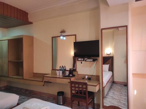 a room with a desk with a television and a bedroom at Hotel Ambarish Grand Residency in Guwahati