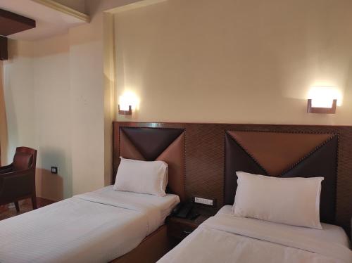 two beds in a hotel room with white sheets at Hotel Ambarish Grand Residency in Guwahati