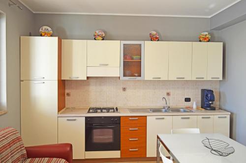 a kitchen with white cabinets and a stove top oven at House Paradise Amedeo in Bauso
