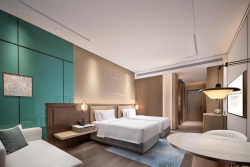 a bedroom with a bed and a table and a couch at Grand Mercure Chengdu East in Chengdu