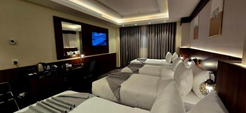 a hotel room with two beds and a desk at Maysan Rehab Al Mysk Hotel in Al Madinah