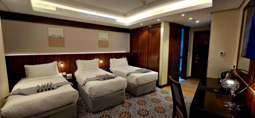a hotel room with two beds and a television at Maysan Rehab Al Mysk Hotel in Al Madinah
