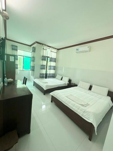 a bedroom with two beds and a desk in it at Nhà nghỉ Phát Thảo in Hà Tiên