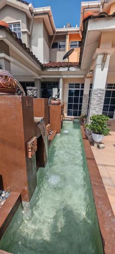 a water fountain in front of a house at Homestay Santai Bertam in Kepala Batas
