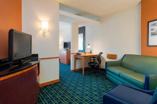 a room with a couch and a tv and a table at Fairfield Inn & Suites Huntingdon Raystown Lake in Huntingdon