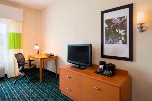 a hotel room with a television on a dresser with a desk at Fairfield Inn & Suites Huntingdon Raystown Lake in Huntingdon