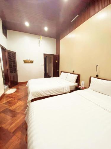 two beds in a room with wooden floors at Rose's Homestay Hue in Hue