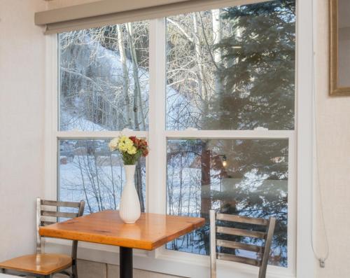 a vase of flowers on a table in front of a window at Mountainside Inn 109 by Alpine Lodging Telluride in Telluride