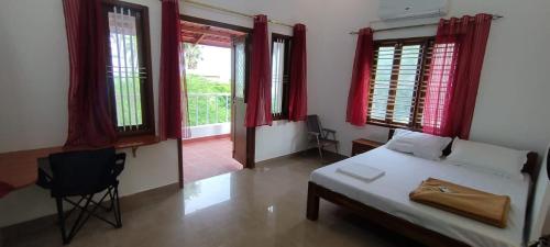 a bedroom with a bed and windows and a chair at Angel Beach Villas - Pondicherry in Puducherry