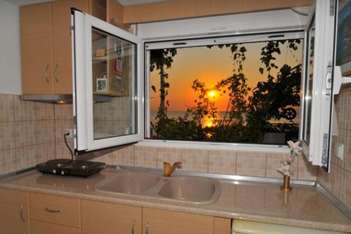 a kitchen sink with a view of a sunset through a window at Sunset Studios in Skala Marion