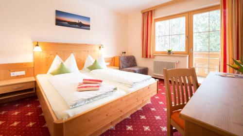 a bedroom with a bed with a desk and a chair at Pension Steiermark in Schladming