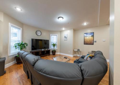 a living room with a large couch and a tv at 233-1 4BR Boston - Cozy Apt near MBTA Station in Boston